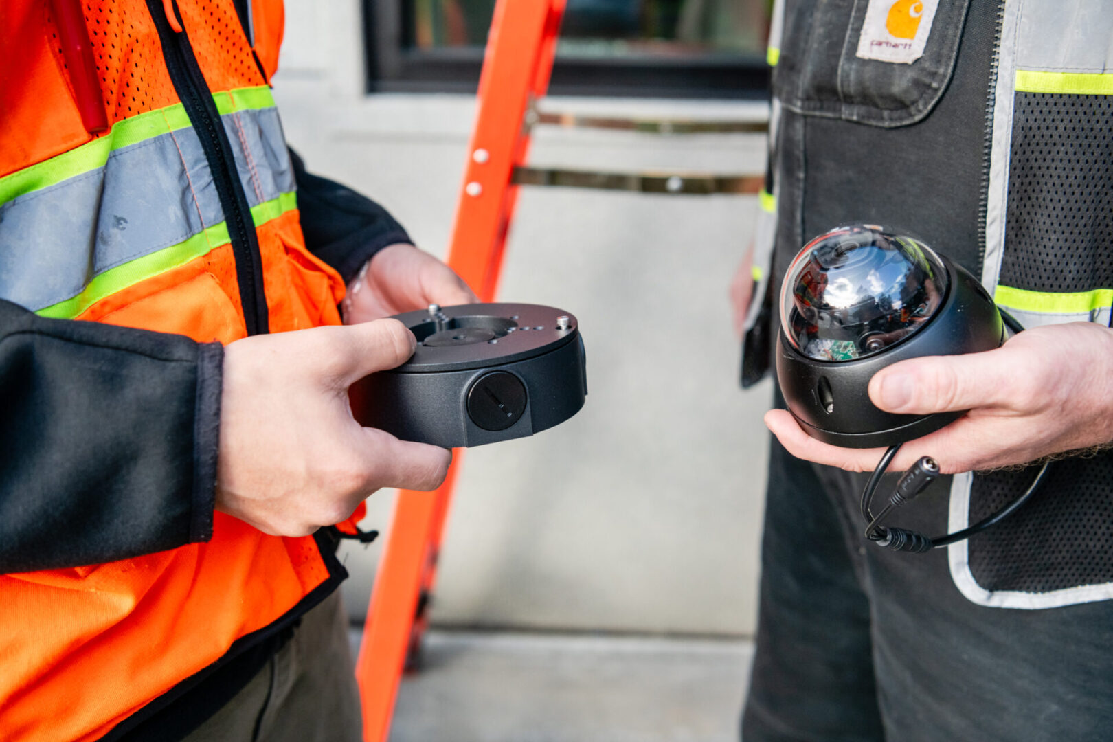 Two men in construction vests holding a camera.